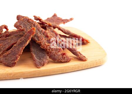 Streifen von Beef Jerky auf einem Schneidbrett isoliert auf einem weißen Hintergrund Stockfoto