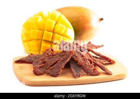 Gourmet Sweet Mango Flavored Beef Jerky auf einem Holzschneidebrettchen Stockfoto