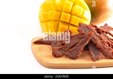 Gourmet Sweet Mango Flavored Beef Jerky auf einem Holzschneidebrettchen Stockfoto