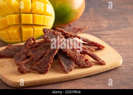 Gourmet Sweet Mango Flavored Beef Jerky auf einem Holzschneidebrettchen Stockfoto