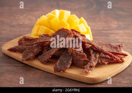 Gourmet Sweet Mango Flavored Beef Jerky auf einem Holzschneidebrettchen Stockfoto