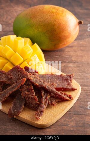 Gourmet Sweet Mango Flavored Beef Jerky auf einem Holzschneidebrettchen Stockfoto