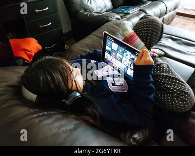 Kleine Mädchen Schulschülerin trägt Kopfhörer Konferenz telefonieren Lernen online mit Remote-Tutor von zu Hause aus. Stockfoto