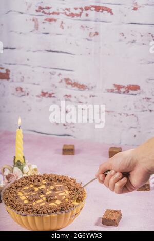 Hand nehmen einen Löffel köstlichen Lucuma Mousse mit Schokolade Brownies auf einen Tisch mit Kerzenleuchter Stockfoto