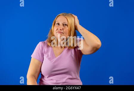 Portrait schöne mittlere Frau mit besorgt und besorgt Gesichtsausdruck, kratzenden Kopf, nachdenklich, im Freien mit Himmel als Hintergrund. Gestenkontra Stockfoto
