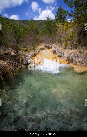 Bergfluss auf einem Bett aus gelben Steinen und trockenen Gräsern, fließt in einen Fluss Pool von kristallklarem Wasser, Sorradipara Schlucht, Fluss Lubierre, Borau, Hue Stockfoto