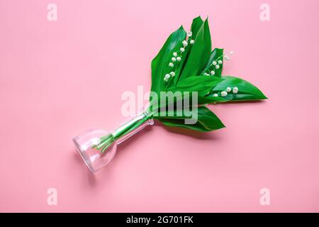 Ein Bukett aus Lillies des Tales in der transparenten Glasvase. Draufsicht mit rosafarbenem, isoliertem Hintergrund Stockfoto