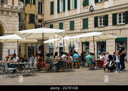 Menschen sitzen in einem Café-Restaurant im Freien auf dem Sankt-Lorenz-Platz, dem historischen Zentrum von Genua, im Sommer Ligurien, Italien Stockfoto