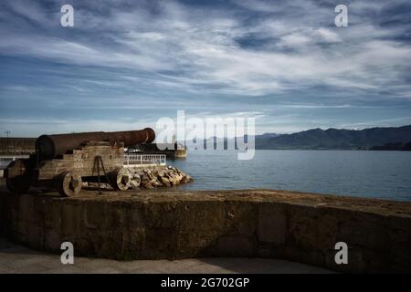 Alte verrostete Kanone, die auf die Bucht von Lastret in Asturien, Spanien, zeigt Stockfoto