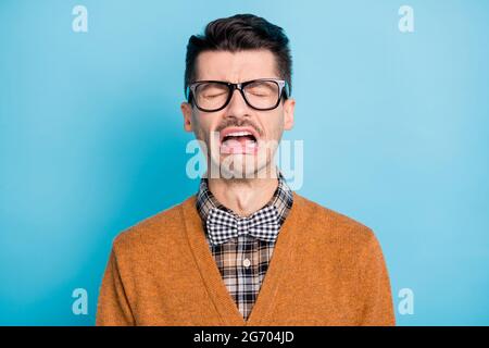 Foto von aufgeregt jungen Geek Mann weinen schlechte Laune tragen Brille kariert Fliege auf blauem Hintergrund isoliert Stockfoto