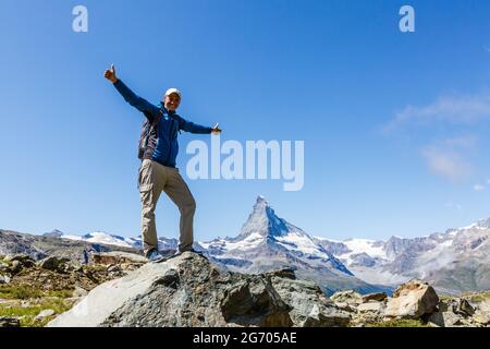 Wanderer auf dem Gipfel eines Passes gegen schneebedeckte Berge in den Alpen. Schweiz, Trek in der Nähe des Matterhorns. Stockfoto