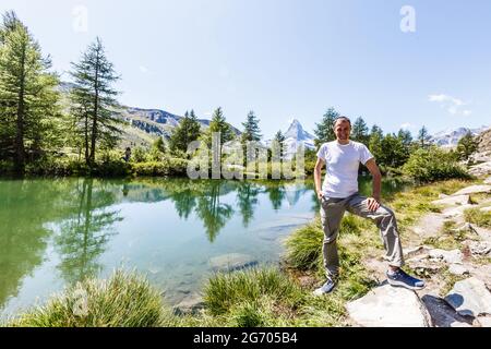 Wanderer auf dem Gipfel eines Passes gegen schneebedeckte Berge in den Alpen. Schweiz, Trek in der Nähe des Matterhorns. Stockfoto