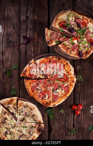 Frisch serviert, drei verschiedene Pizzen. Draufsicht. Holzhintergrund mit Platz für Text. Stockfoto