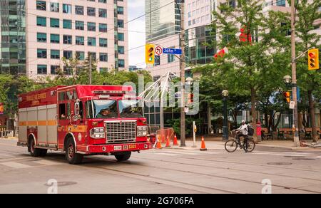 TORONTO, KANADA - 06 05 2021: Red Toronto Fire Services Squad schwerer Rettungswagen, der vor der Metro Hall mit 27 Stockwerken von der King zur John Street fährt Stockfoto