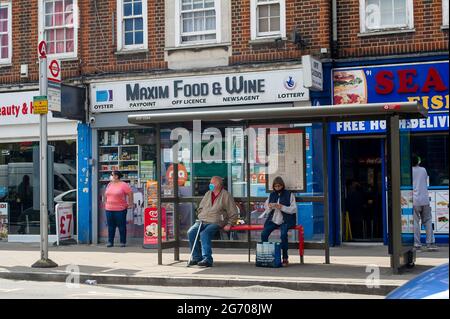 West Drayton, London Borough of Hillingdon, Großbritannien. Juli 2021. Menschen mit Gesichtsmasken warten an einer Bushaltestelle. Boris Johnson wird voraussichtlich ab dem 19. Juli 2021 die gesetzliche Vorschrift zum Tragen von Gesichtsmasken in öffentlichen Verkehrsmitteln aufheben, was jedoch bei Reisenden Besorgnis erregend ist, von denen viele ihre Gesichtsmasken weiterhin tragen wollen, da die Anzahl der Covid-19-Fälle deutlich ansteigt. Quelle: Maureen McLean/Alamy Stockfoto