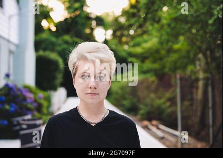 Junge nicht-binäre Person mit Kettengliederkette und schwarzem T-Shirt Stockfoto