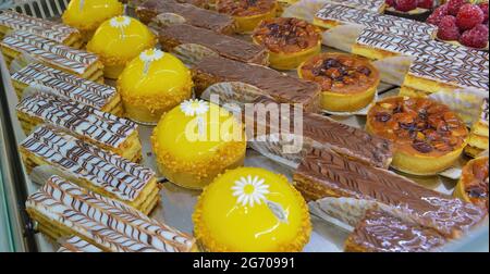 Köstliche bunte Backwaren und Kuchen auf einem Marktstand. Himbeerkörtchen, Schokoladenkuchen und Obsttörtchen. Stockfoto