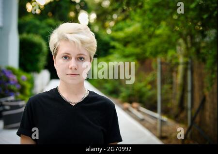 Junge nicht-binäre Person mit Kettengliederkette und schwarzem T-Shirt von der Mitte nach links Stockfoto