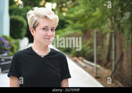 Lächelnde junge nicht-binäre Person mit blondem Haar Stockfoto