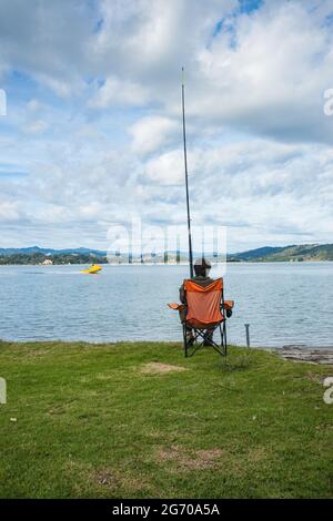 Whakatane New Zealand - Mai 26 2012; Einzelfischer am Ohiwa Harbour Rückansicht geduldig und hoffentlich wartet. Stockfoto