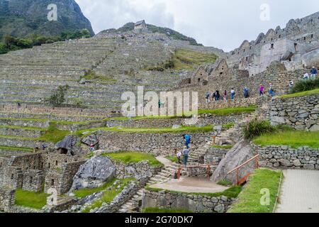 MACHU PICCHU, PERU - 18. MAI 2015: Besuchermassen im Haus des Hohenpriesters in den Ruinen von Machu Picchu, Peru. Stockfoto