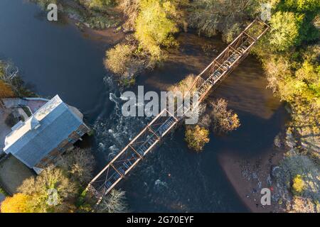 Luftaufnahme des Daches einer alten, verlassenen Mühle an einem Fluss in New Jersey mit Bahngleisen über dem Fluss, im Herbst. Stockfoto