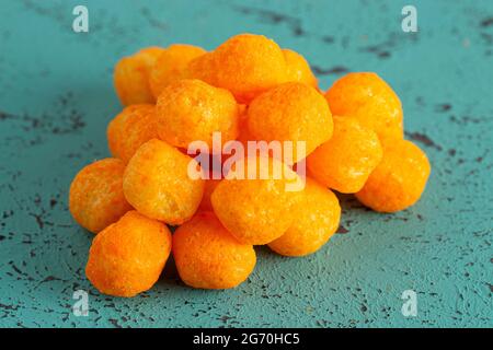 Mit Käse überzogene Kugelsnacks auf einem Teal-Tisch Stockfoto