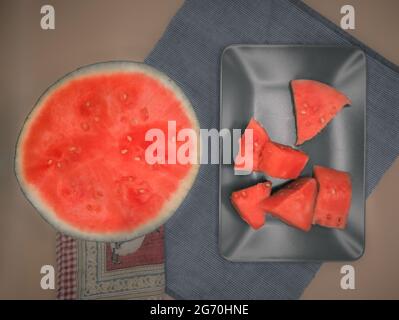 Sommerfrucht.Rote Wassermelone in zwei Hälften geschnitten und in Stücke zu essen serviert auf einem Teller, wie von oben gesehen. Stockfoto