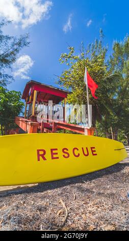 Roter Rettungsschwimmer-Turm und gelbes Rettungsbrett mit roter Warnflagge Stockfoto