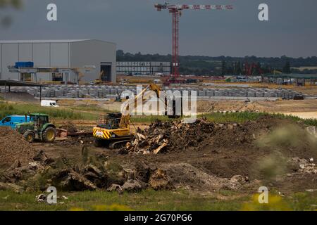 West Hyde, Großbritannien. Juli 2021. Ein Bagger bewegt die Überreste von gefällten Bäumen vor präzisionsgefertigte Tunnelsegmente am Standort South Portal für den Tunnelabschnitt Chiltern der Hochgeschwindigkeitsstrecke HS2. HS2 Ltd hat den Start der zweiten 2,000-Tonnen-Tunnelbohrmaschine (TBM) bekannt gegeben, die Cecilia nach der Astronomin und Astrophysikerin Cecilia Payne-Gaposchkin benannt wurde, um einen zweiten 10-Meilen-Tunnel unter den Chilterns auszugraben. Kredit: Mark Kerrison/Alamy Live Nachrichten Stockfoto