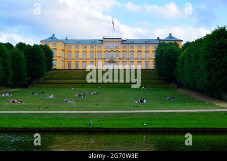 Kopenhagen, Dänemark - 2021. Juli: Menschen entspannen sich auf dem Rasen vor dem Schloss Frederiksberg und den Gärten (Frederiksberg Slot) Stockfoto