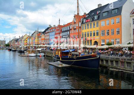 Kopenhagen, Dänemark - 2021. Juli: Farbenfrohe alte Häuser, Cafés und Restaurants, mit Booten, die an einem düsteren Tag entlang des Kanals von Nyhavn (New Harbour) anlegen Stockfoto