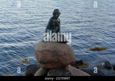 Kopenhagen, Dänemark - 2021. Juli: Die kleine Meerjungfrau-Statue (Den lille Havfrue), die auf einem Felsen am Wasser an der Langelinie-Promenade dargestellt ist Stockfoto