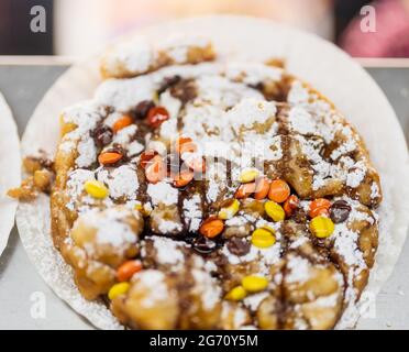 Carnival Funnel Cake gekrönt mit Puderzucker, Karamell und M & Ms. Stockfoto