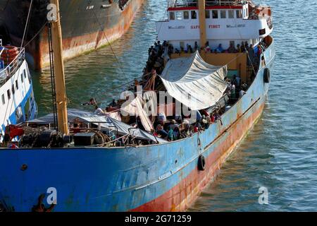 Ein Schiff voller Flüchtlinge traf ein anderes Schiff, als es versuchte, zwischen zwei Schiffen in den warmen Gewässern von Benin, Westafrika, anzudocken. Stockfoto