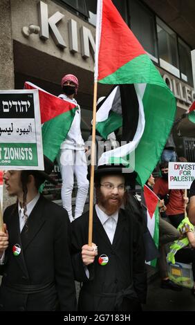 London, Großbritannien. Juli 2021. Protestierende der orthodoxen jüdischen antizionistischen Gruppe, der Neturei Karta, halten während eines Protestes palästinensische Fahnen und Plakate vor dem King's College.Studenten und andere Protestierende gehen auf eine Tour durch die Londoner Universitäten, um einen Boykott für alle israelischen akademischen und kulturellen Institutionen zu fordern, in Solidarität mit dem Kampf gegen die Beendigung der israelischen Universitäten Besetzung, Kolonisierung und Apartheid-System in Israel. (Foto von Martin Pope/ SOPA Images/Sipa USA) Quelle: SIPA USA/Alamy Live News Stockfoto