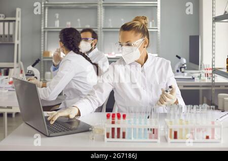 Wissenschaftler, die in einem medizinisch-wissenschaftlichen Labor forschen und an einem Laptop arbeiten Stockfoto