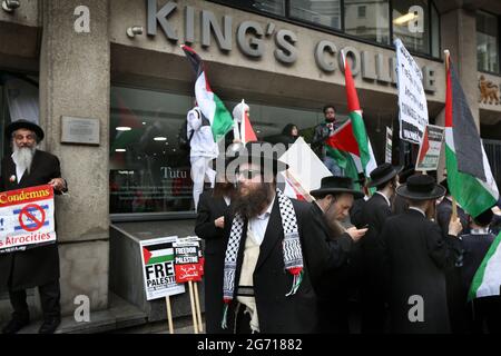 London, Großbritannien. Juli 2021. Protestierende der orthodoxen jüdischen antizionistischen Gruppe, der Neturei Karta, halten während eines Protestes palästinensische Fahnen und Plakate vor dem King's College.Studenten und andere Protestierende gehen auf eine Tour durch die Londoner Universitäten, um einen Boykott für alle israelischen akademischen und kulturellen Institutionen zu fordern, in Solidarität mit dem Kampf gegen die Beendigung der israelischen Universitäten Besetzung, Kolonisierung und Apartheid-System in Israel. Kredit: SOPA Images Limited/Alamy Live Nachrichten Stockfoto