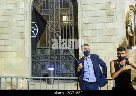 Barcelona, Spanien. Juli 2021. Der Protestierende in einer Klage wird während des Protestes mit einer anarchistischen Flagge gesehen.Demonstranten gehen auf die Straßen von Barcelona gegen die LGTBI-Phobie und den Tod von Samuel Luiz, einem 24-jährigen homosexuellen jungen Mann, der letzte Woche bei einem homophoben Angriff in der Stadt A Coruña, Spanien, ermordet wurde. Kredit: SOPA Images Limited/Alamy Live Nachrichten Stockfoto