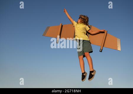 Kids Leader und Gewinner, Erfolg beginnt. Junge Pilot fliegen gegen einen blauen Himmel. Aufgeregt Kind Junge spielen mit Spielzeug Jetpack Flügel Superheld im Park. Stockfoto