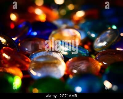 Eine Gruppe lebendiger Glassperlen mit farbenfrohen, hellen Lichtern, die auf einem verschwommenen Hintergrund reflektiert werden Stockfoto