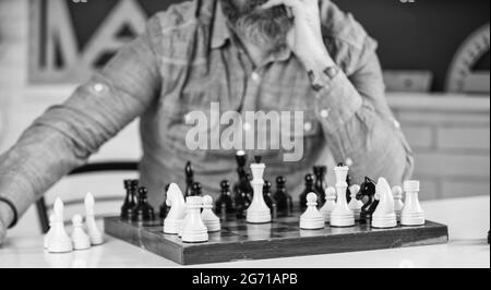 Turnierkünste. Schachfiguren auf Holzbrett. Fokussierter Lehrer. Denken an Angriff und das Einfangen gegnerischer Schachfiguren. Denken an nächstes Stockfoto