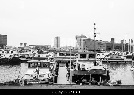 AMSTERDAM, NIEDERLANDE. 06. JUNI 2021. Schöner Blick auf einen Schiffskanal und Brücken. Schwarzweiß-Fotografie. Kleine Boote, Schiffe und Bargen Stockfoto