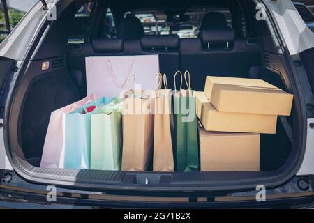 Voll Papier und Tasche Einkaufstaschen im Warenkorb.Bunte Tasche und braune Box im hinteren Kofferraum Lagerung. Shopping sucht oder shopaholic Konzept. Stockfoto