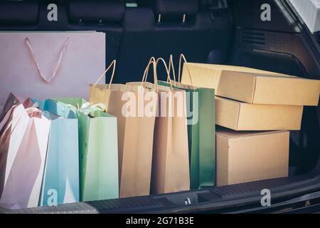 Voll Papier und Tasche Einkaufstaschen im Warenkorb.Bunte Tasche und braune Box im hinteren Kofferraum Lagerung. Shopping sucht oder shopaholic Konzept. Stockfoto