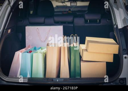 Voll Papier und Tasche Einkaufstaschen im Warenkorb.Bunte Tasche und braune Box im hinteren Kofferraum Lagerung. Shopping sucht oder shopaholic Konzept. Stockfoto