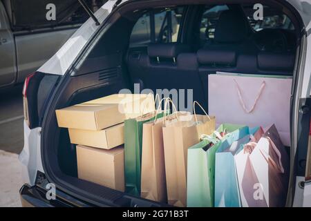 Voll Papier und Tasche Einkaufstaschen im Warenkorb.Bunte Tasche und braune Box im hinteren Kofferraum Lagerung. Shopping sucht oder shopaholic Konzept. Stockfoto