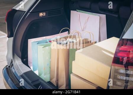 Voll Papier und Tasche Einkaufstaschen im Warenkorb.Bunte Tasche und braune Box im hinteren Kofferraum Lagerung. Shopping sucht oder shopaholic Konzept. Stockfoto