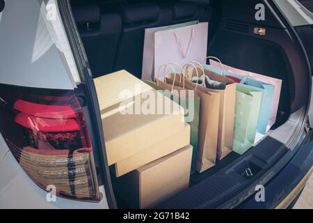 Voll Papier und Tasche Einkaufstaschen im Warenkorb.Bunte Tasche und braune Box im hinteren Kofferraum Lagerung. Shopping sucht oder shopaholic Konzept. Stockfoto