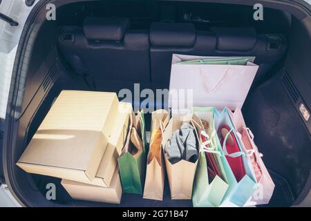 Voll Papier und Tasche Einkaufstaschen im Warenkorb.Bunte Tasche und braune Box im hinteren Kofferraum Lagerung. Shopping sucht oder shopaholic Konzept. Stockfoto